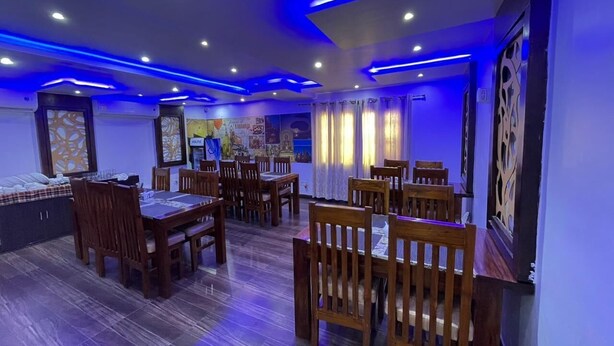 Een eetruimte met houten tafels en stoelen, plafondlampen en wanddecoraties.