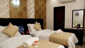 Een hotelkamer met twee bedden, een minibar, een spiegel en een wandairconditioner.