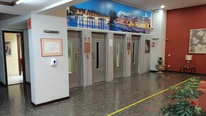 A hotel lobby with a cityscape mural, multiple elevators, a reception desk, and a potted plant. - Romantic Apartment in Sevilla Near Giralda (Seville)