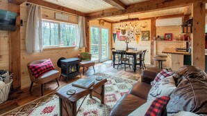 A cozy cabin interior with a wooden interior, a fireplace, a dining area, and a living room with a sofa and chairs. - Cozy Cabin w/ hot tub, 2 mi from Lake George, 24 acres, fireplace (Hague)