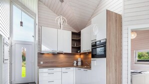 A modern kitchen with white cabinets, a wooden countertop, and a built-in oven. - Vacation home with trampoline, sauna & fireplace - up to 3 dogs - fully fenced (Schönberg (Holstein))