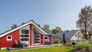 A red house with a large porch, a dining area, and a barbecue grill. - Vacation home with trampoline, sauna & fireplace - up to 3 dogs - fully fenced (Schönberg (Holstein))