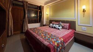 A hotel room with a large bed, a wardrobe, a mirror, and a nightstand with a lamp. - Irra Homes • 2BHK Apartment • Panoramic Valley View (Shimla)