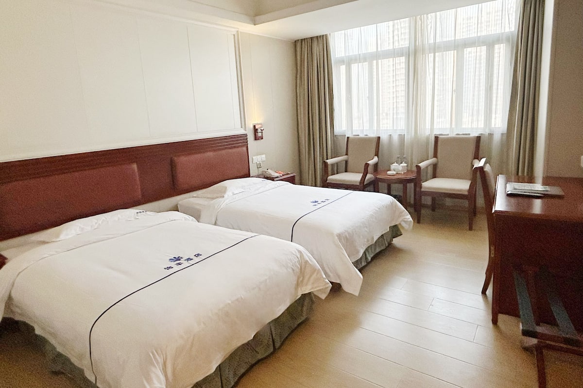 Une chambre d’hôtel avec deux lits, un bureau et une chaise.