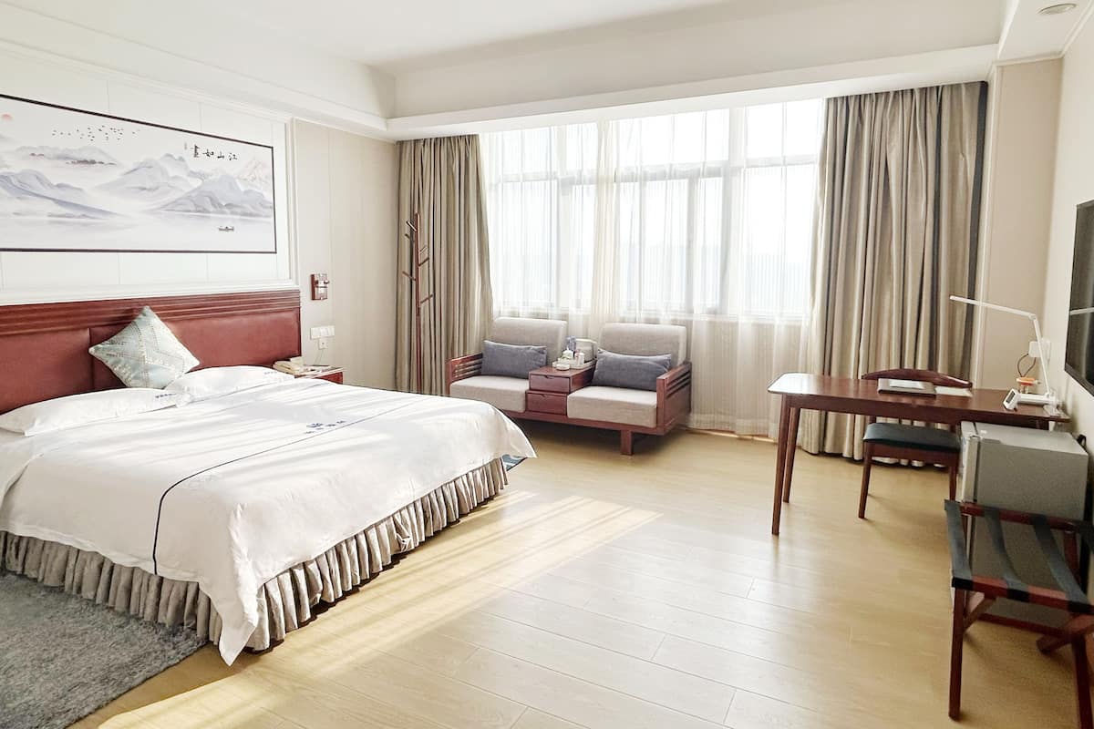 Une chambre d’hôtel avec un lit, un bureau, une chaise, une télévision et un tableau au mur.