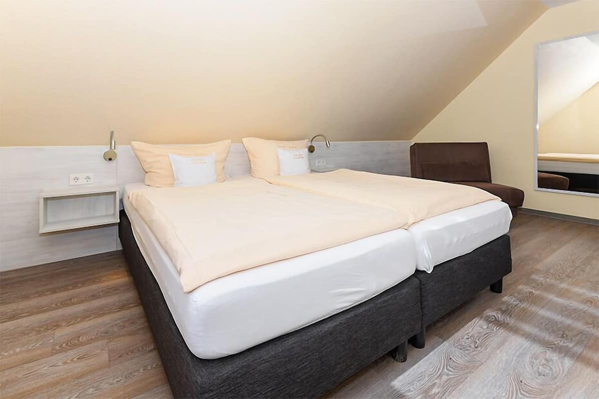 A bedroom with a bed, bedside tables, a chair, and a mirror.
