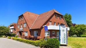 A red-brick building with a sloped roof, a signboard for Pension Nordkap, and a blue parking sign.