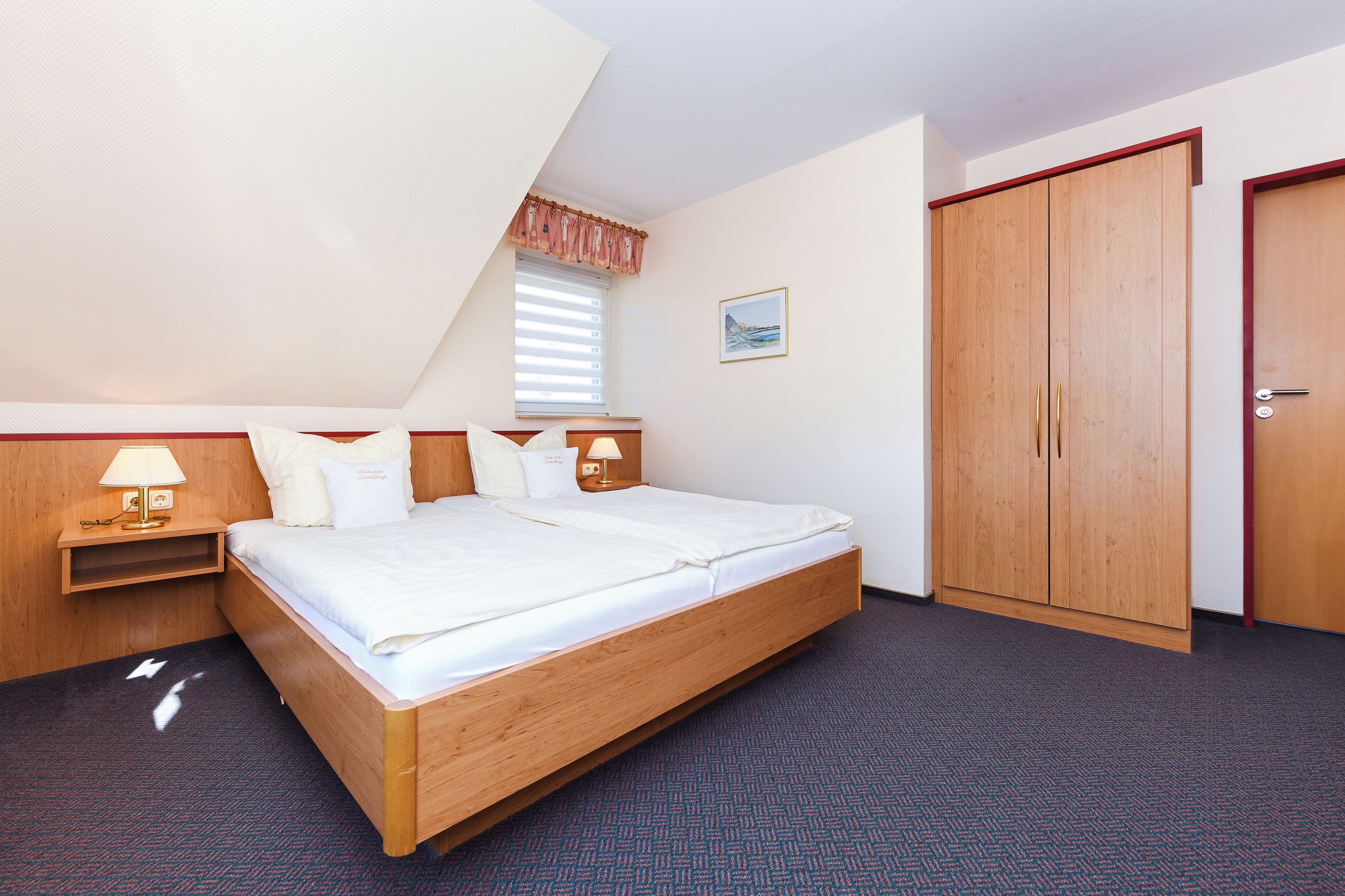 A bedroom with a bed, bedside tables, a window, a wardrobe, and a door.