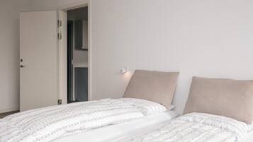 A bedroom with a bed, a door, and a wall-mounted light fixture.