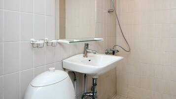 Un baño con un lavamanos blanco, repisa de vidrio, inodoro y ducha.