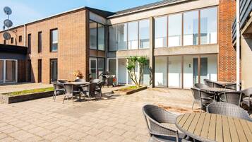 Un edificio moderno con un patio amueblado con asientos exteriores y una parrilla.