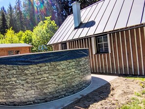 A stone water feature with a circular design, a wooden building with vertical siding, and a metal roof. - U potůčku by Interhome (Harrachov)