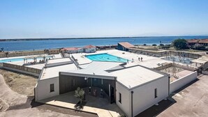 A rooftop pool area with multiple swimming pools and a clear view of the sea. - Dominica by Interhome (Le Barcarès)
