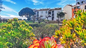 A coastal building with balconies, a clear sky, and a garden with various plants. - Dominica by Interhome (Le Barcarès)