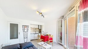 Ett kompakt bostadsutrymme med en soffa, ett matbord och ett litet kök.
