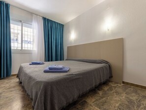 Une chambre d’hôtel avec un lit, des rideaux, une fenêtre et une tête de lit.