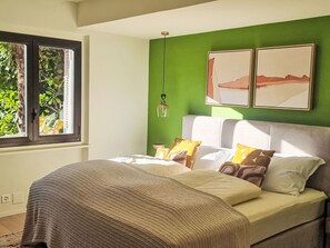 A bedroom with a bed, green walls, a window, and two framed pictures. - Villa Chiara by Interhome (Brissago)