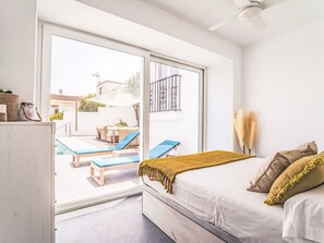 A bedroom with a bed, a window, and a view of an outdoor pool area. - Calam de Luna by Interhome (Peñiscola)