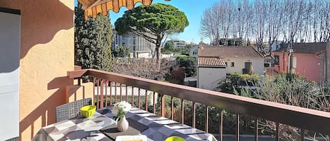 A balcony with a table, chairs, a yellow bowl, and a magazine.