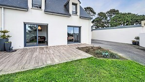 A modern house with a sloped roof, large windows, and a wooden deck. - Maison de la Ria by Interhome (Plouhinec Morbihan)