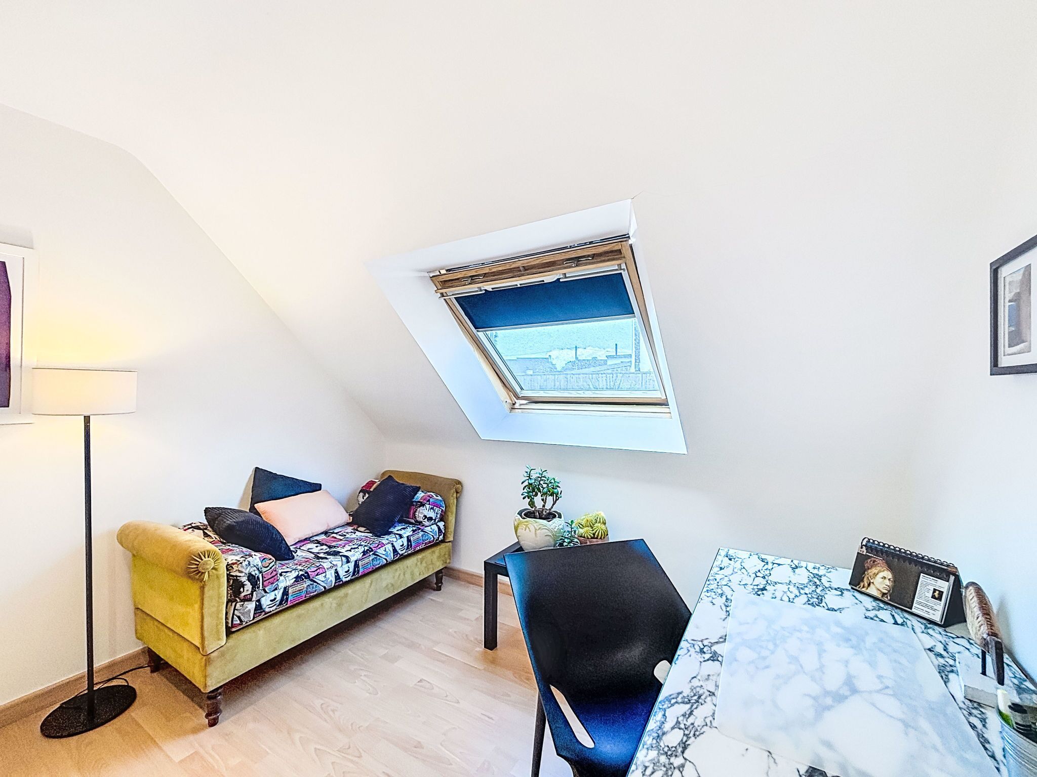 Una habitación con sofá, sillón, una mesita, lámpara, ventana con vistas y un cuadro en la pared.