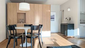 Une cuisine moderne avec des meubles en bois, une table à manger avec des chaises et un luminaire suspendu.