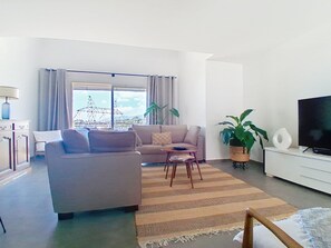 A living room with a sofa, a coffee table, a TV, and a large window with curtains. - Domaine de l'Etoile by Interhome (Saint-Jeannet)