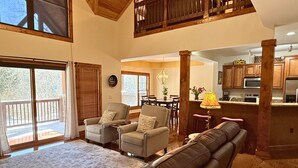 A spacious living area with a fireplace, a dining table, and a kitchen area. - Beautiful Rustic Mountain Getaway at Elkmont (Banner Elk)