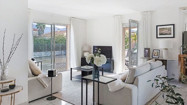 A modern living room with a sofa, a coffee table, a TV, and a balcony with a view. - Villa Brouilla by Interhome (Brouilla)