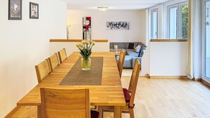 A dining area with a wooden table, chairs, and a vase of flowers. - Happy Living by Interhome (Vandans)