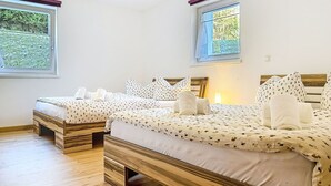 A hotel room with two wooden beds, white bedding, and a view of greenery through the windows. - Happy Living by Interhome (Vandans)