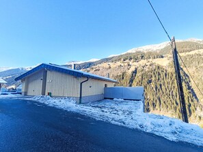 Un bâtiment doté d’un toit en pente, d’une allée pavée et ayant une chaîne de montagnes en arrière-plan.