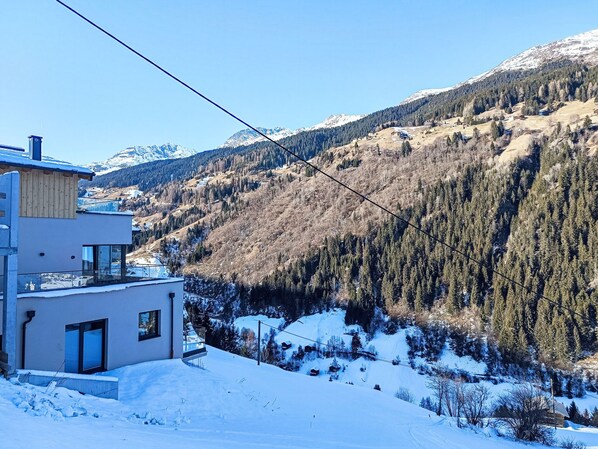 Un bâtiment moderne doté d’un balcon donnant sur un paysage montagneux enneigé.