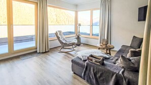 Une pièce spacieuse avec un grand canapé, un fauteuil à bascule et une petite table.