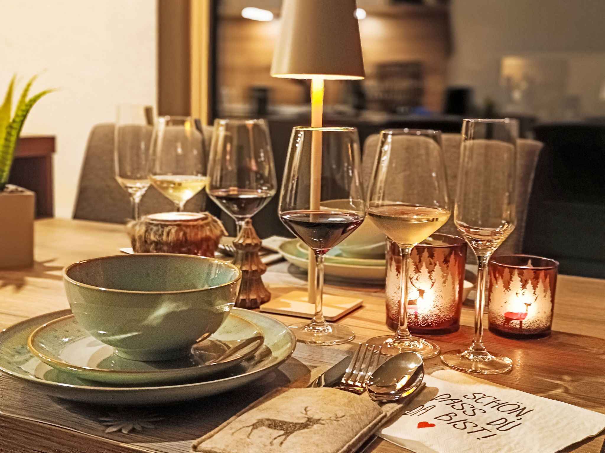 Ein Esstisch, gedeckt mit unterschiedlichem Glas, Tellern und einem Kerzenständer.