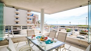 Ein Balkon mit Esstisch, der auf einen Parkplatz und einige Gebäude blickt.