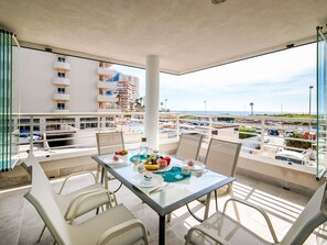 Ein Balkon mit Esstisch, der auf einen Parkplatz und einige Gebäude blickt.