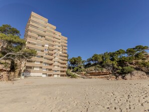 A multi-story building with balconies, situated on a sandy area with trees in the background. - Los Delfines by Interhome (Miami Platja)