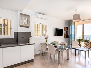 A modern kitchen with a built-in stove, a dining area with a glass table, and a balcony with a view. - El Faro on the Beach by Interhome (Mijas Costa)