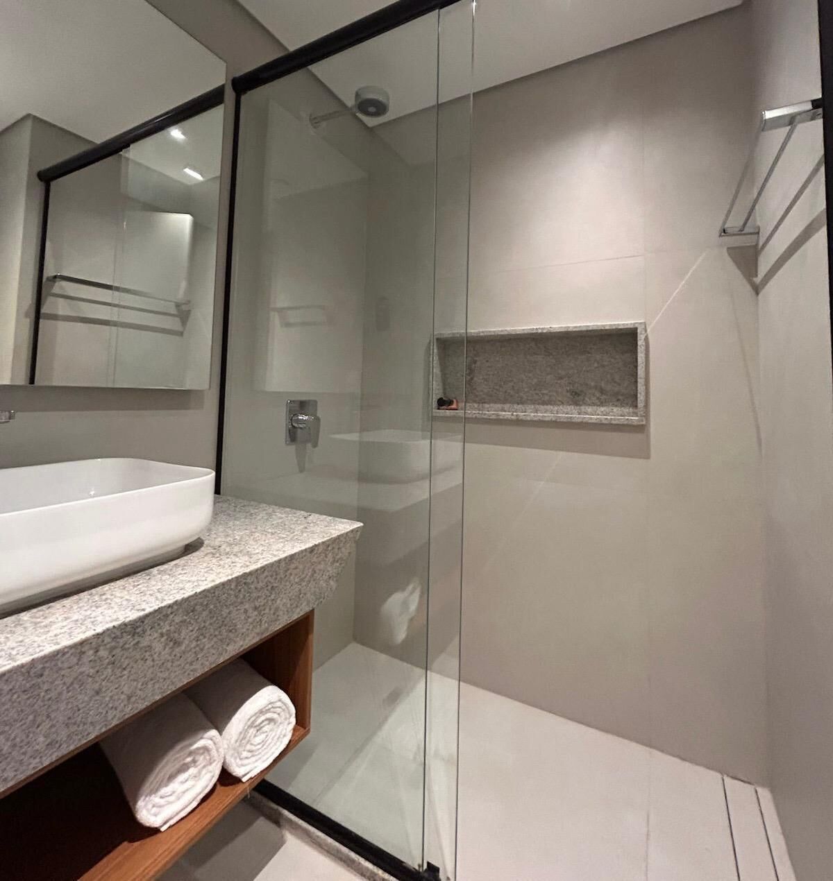 Une salle de bain moderne avec une douche à parois de verre, un lavabo blanc et un comptoir en marbre.