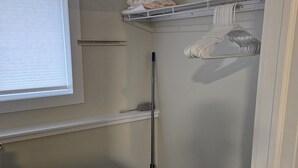 Una stanza piccola e stretta con una finestra, una scopa, uno straccio e un appendiabiti.