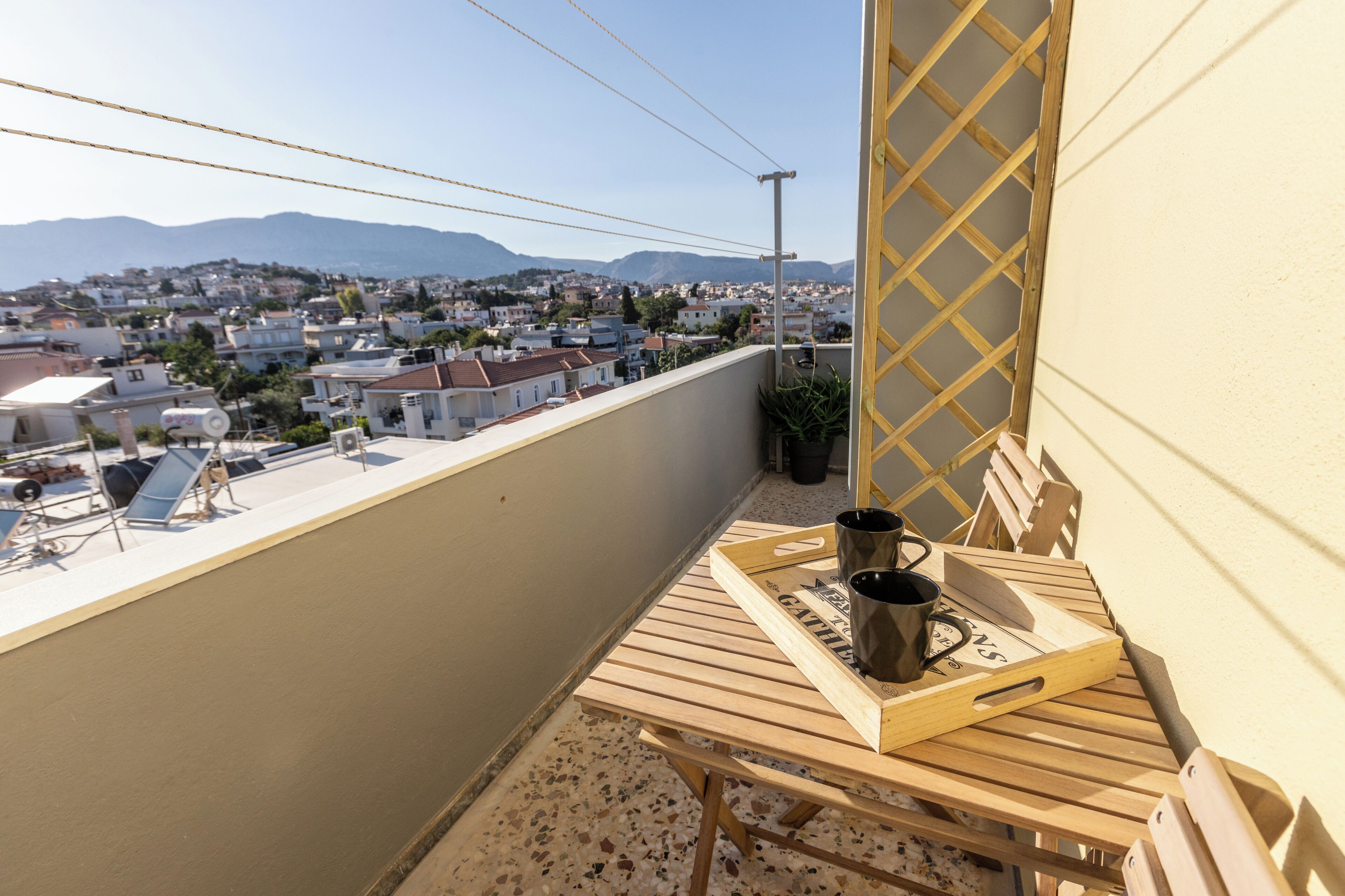 A balcony with a wooden table, two black mugs, and a tray with the word 'GATELLI' on it.