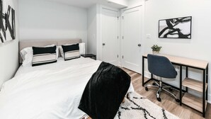 Ett modernt sovrum med en säng, sängbord, ett skrivbord och en stol.