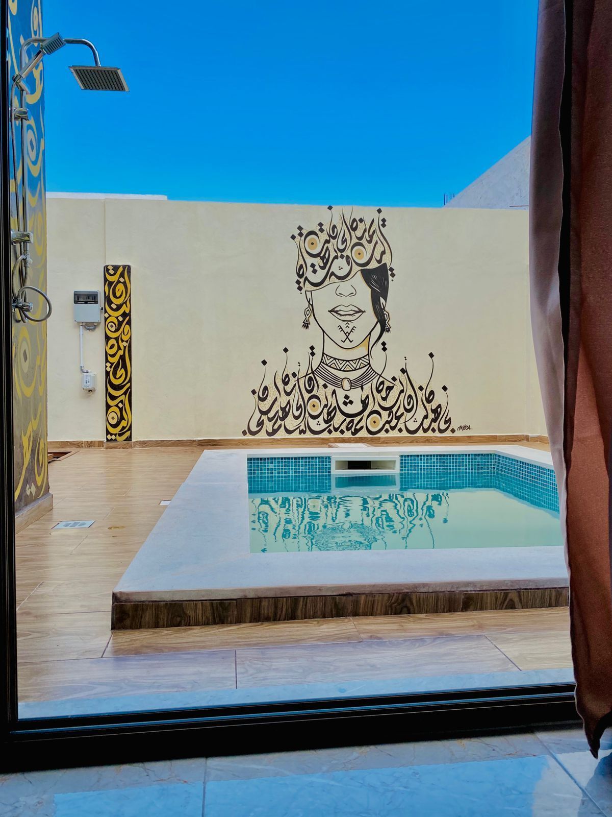 Une piscine agrémentée d’une fresque murale décorative, d’un espace douche et d’un sol carrelé.