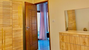 A bedroom with a bed, a wooden wardrobe, a dresser, and a ceiling light fixture. - Villa sabrina gold (Djerba Midun)