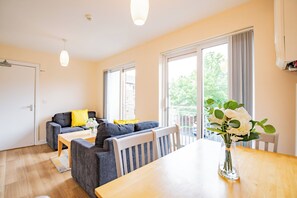 Ein modernes Wohnzimmer mit einer Couch, einem Esstisch und einer Blumenvase.