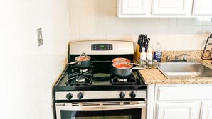 Una cocina con armarios blancos, estufa, horno y encimera de granito.