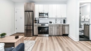 A modern kitchen with white cabinets, stainless steel appliances, and a wooden accent wall.