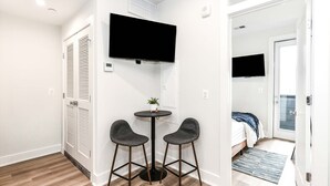 A small room with a TV, two chairs, a small table, and a door leading to another room.