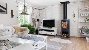 Una sala de estar moderna con chimenea, muebles blancos y un televisor.